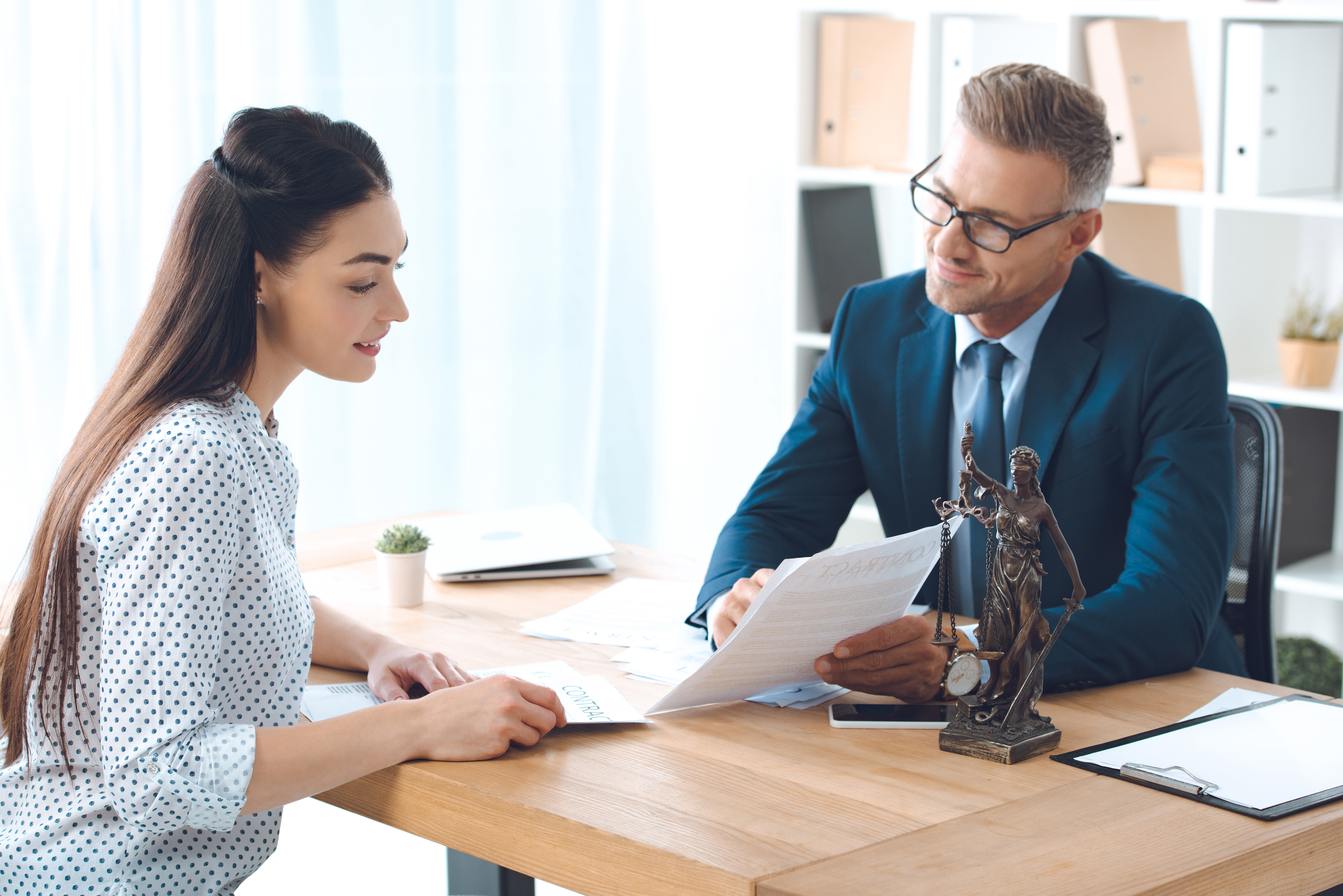 smiling lawyer showing papers to happy client in office